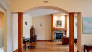 A spacious living room with a fireplace, wooden flooring, and a map on the wall. - Fort Wine Manor: Entire Private Estate Home (Langley Township)