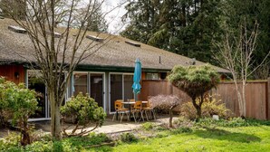 A house with a patio, a dining area with chairs and a table, and a small garden with various plants and trees. - Fort Wine Manor: Entire Private Estate Home (Langley Township)