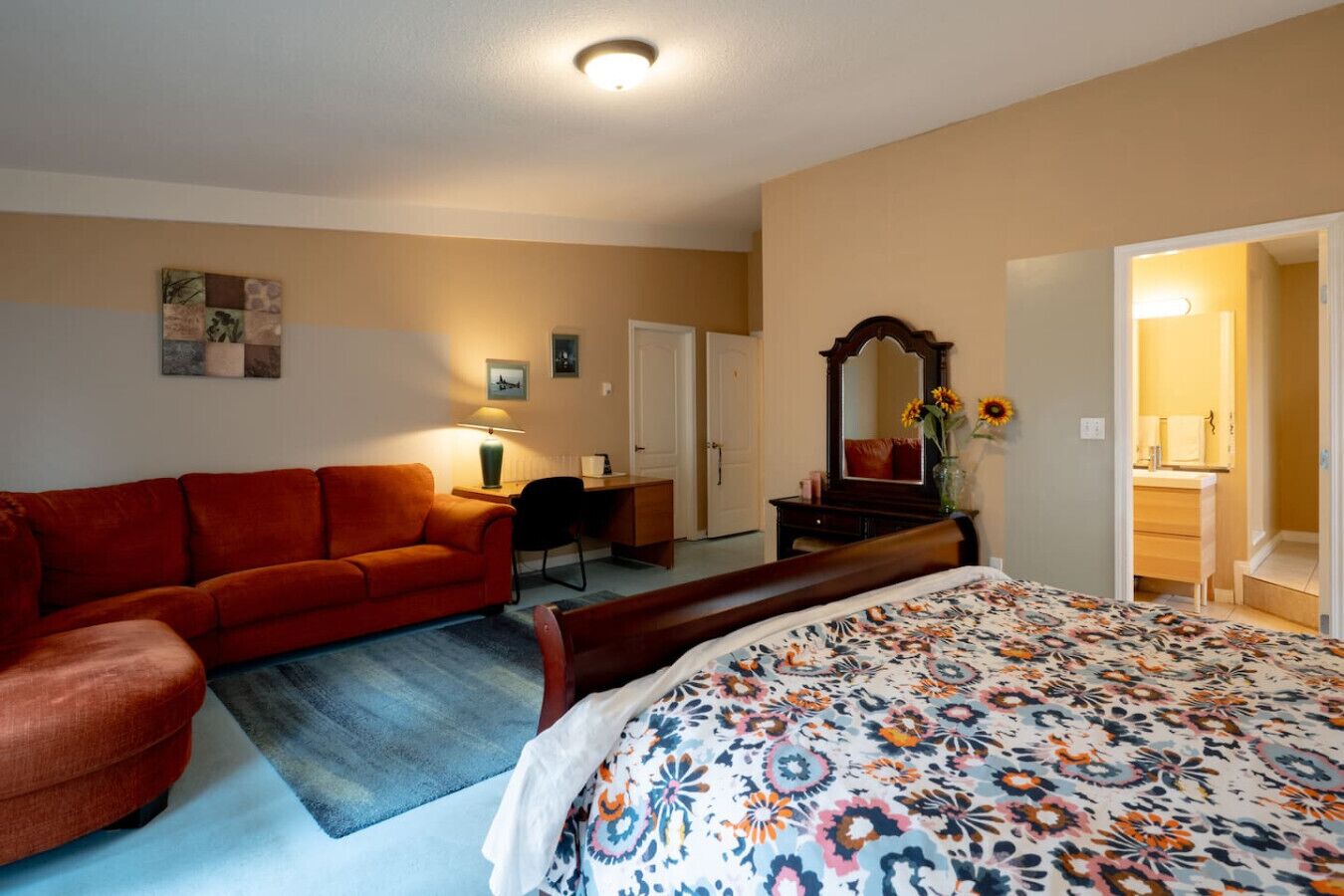 Un dormitorio con una cama, un sofá rojo, un escritorio y una silla.