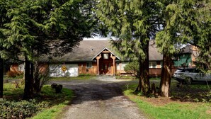 A wooden cabin with a gravel driveway, surrounded by trees. - Fort Wine Manor: Entire Private Estate Home (Langley Township)
