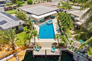 A residential property with a swimming pool, outdoor seating, and a dock. - Waterfront Villa | Pool, Bikes, Kayaks | Sleeps 14 (Pompano Beach)