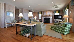 A spacious living room with a fireplace, a television, and a ceiling fan.
