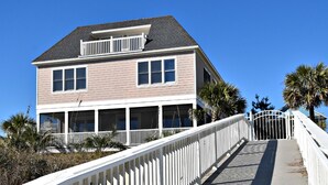 A two-story house with a balcony, a covered porch, and a wooden staircase leading to the entrance.