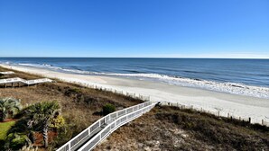 A beach with a white wooden walkway leading to the shore.