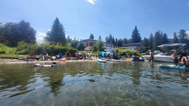 Eine Seenlandschaft mit klarem Wasser, Booten und Menschen, die die Umgebung genießen.