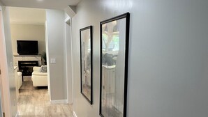 Ein Korridor mit Holzboden, grauen Wänden und gerahmten Kunstwerken.