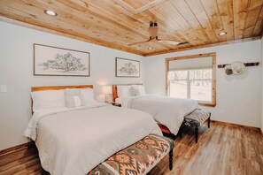 Une chambre avec deux lits, un plancher en bois et un ventilateur de plafond.