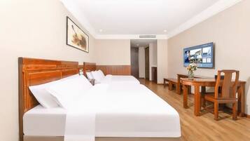 Een hotelkamer met een groot bed, een houten hoofdbord, een bureau met stoel en een televisie aan de muur.