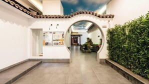 A corridor with a tiled floor, an archway, a wall with a display, and a green hedge. - No.1 Boutique Hotel (Changshu Qinhu Branch) (Changshu)