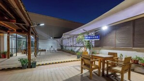 An outdoor patio area with wooden flooring, tables, and chairs. There is a sign in a foreign language, and potted plants are visible. - No.1 Boutique Hotel (Changshu Qinhu Branch) (Changshu)