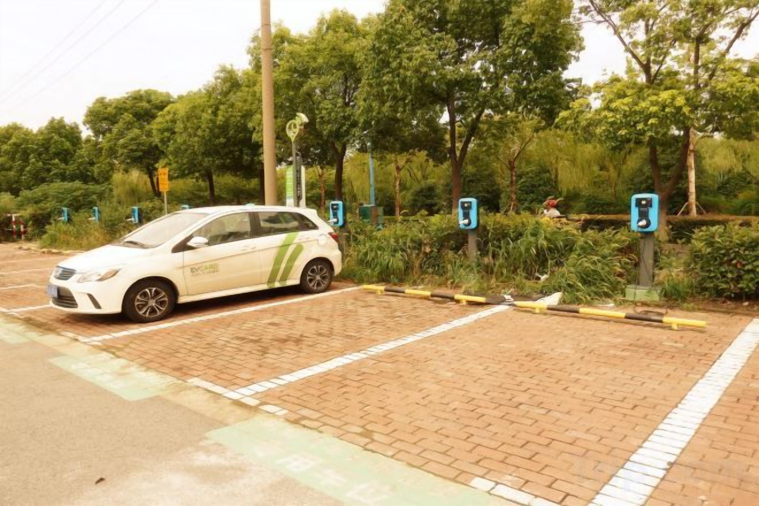 A parking area with a white car parked near a charging station.