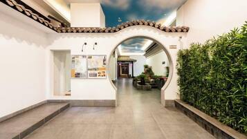 A corridor with a tiled floor, a decorative ceiling, and a wall-mounted display case.