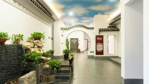 A hotel corridor with a stone wall, potted plants, a staircase, and a ceiling with a cloud design. - No.1 Boutique Hotel (Changshu Qinhu Branch) (Changshu)