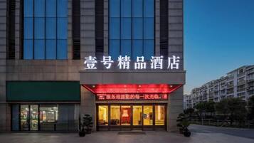 Een hotel met een moderne gevel, grote ramen en een opvallende ingang met verlichte borden.