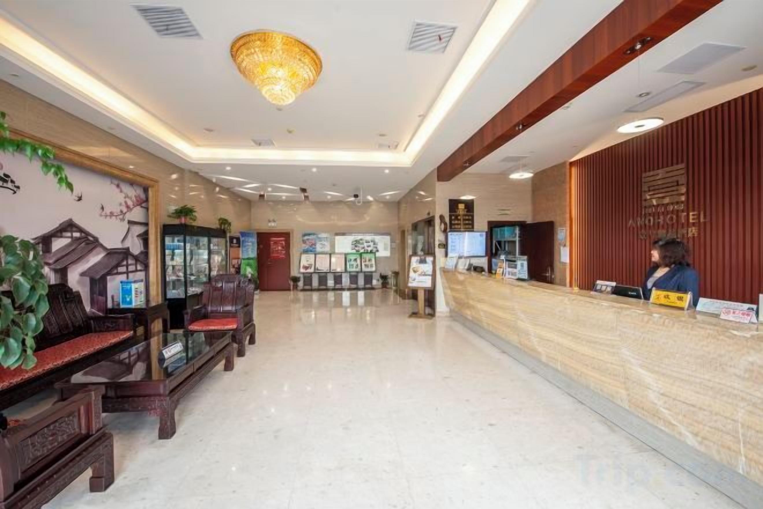 A hotel reception area with a reception desk, seating area, and a chandelier.