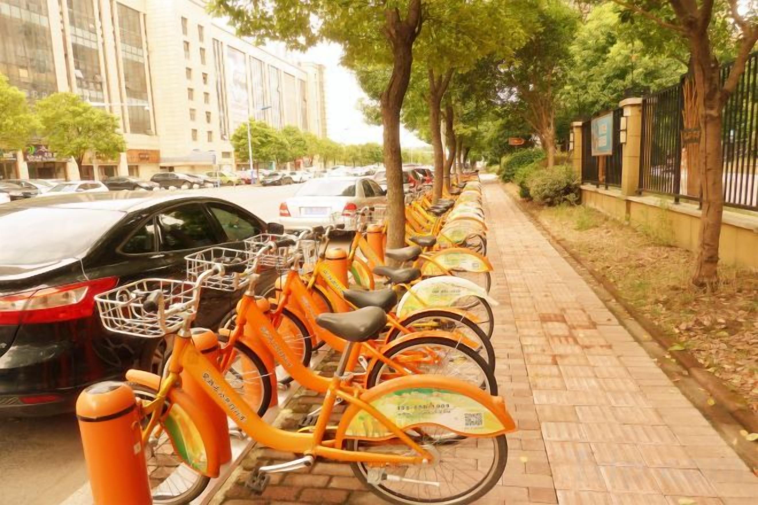 A row of orange bicycles parked on a brick sidewalk.
