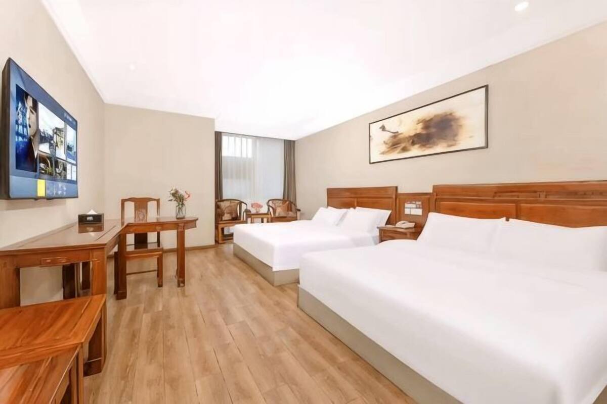 Une chambre d’hôtel avec deux lits, un bureau, une chaise et un téléviseur.