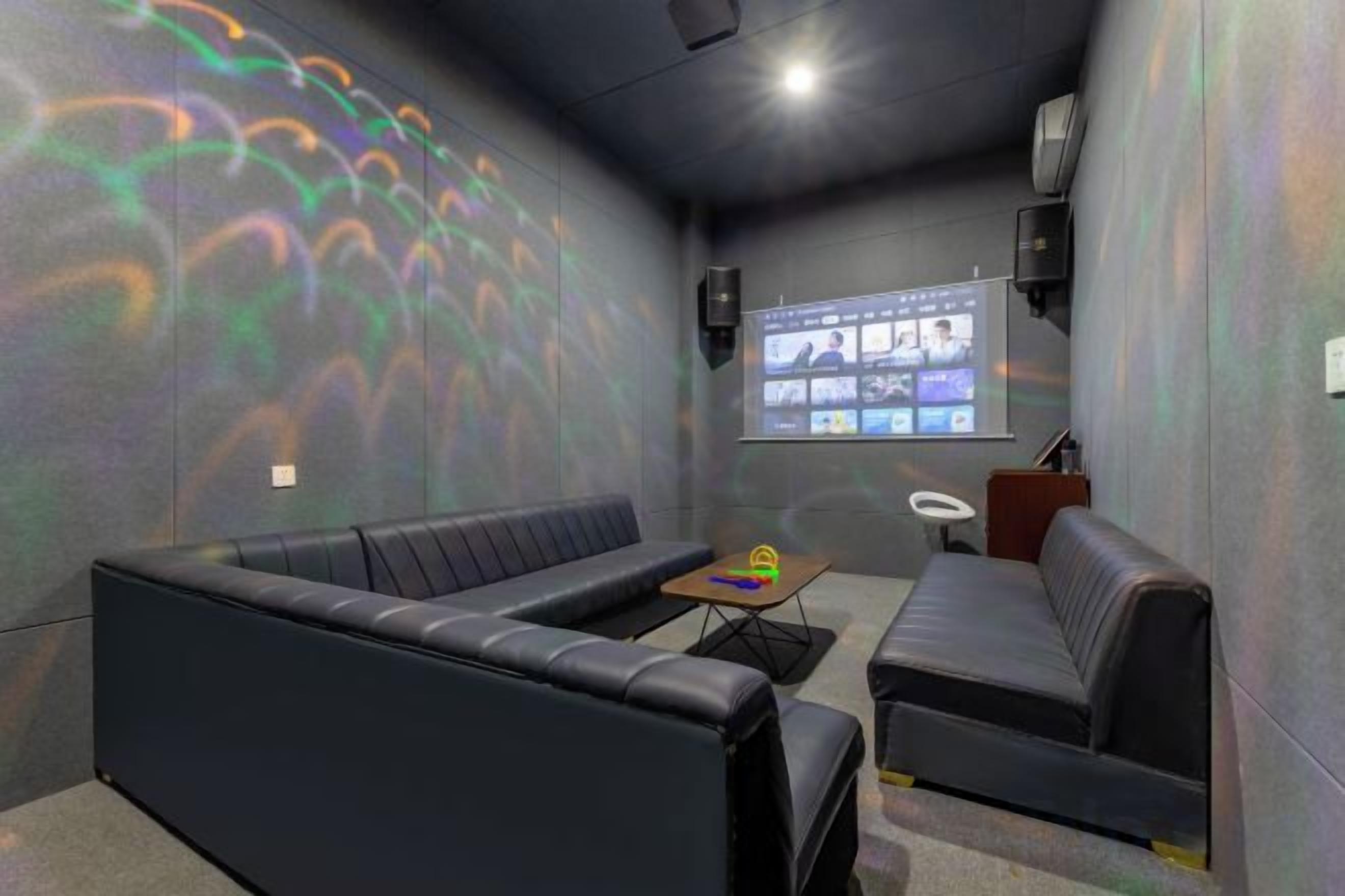 A room with a projection screen displaying a presentation, a sofa, a small table, and a wall-mounted speaker.