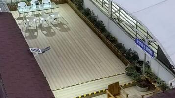 A rooftop terrace with a seating area, potted plants, and a clear sky.