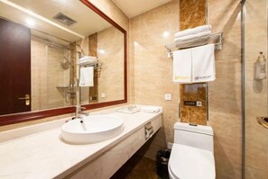 Un baño con lavamanos, espejo, inodoro y toallero.