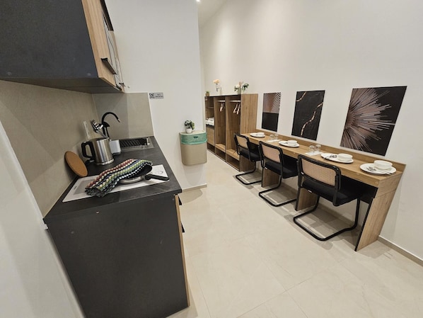 A modern kitchen with a dining area, featuring a stove, sink, and a dining table set for four.
