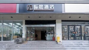 A hotel entrance with a modern facade, glass doors, and a visible staircase leading to the entrance.
