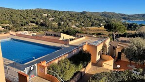 Una piscina en la azotea con vista a una colina y un cuerpo de agua a lo lejos.