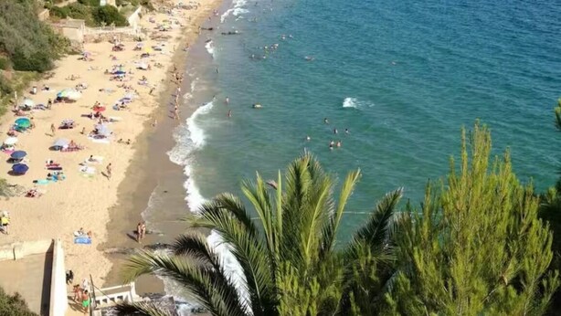Una playa con gente, sombrillas y una vista despejada del mar.