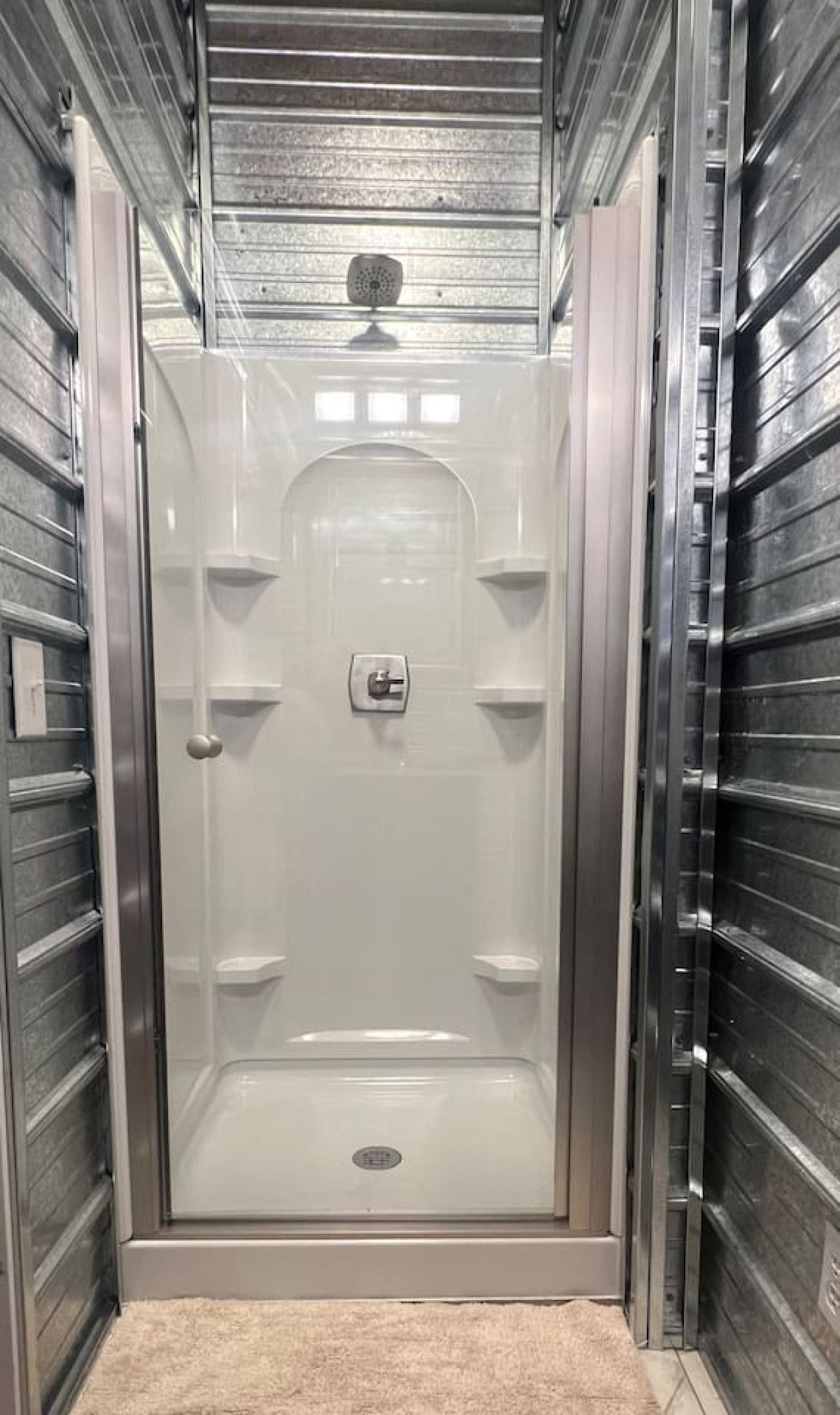 A walk-in shower with a glass door, a control panel, and a showerhead.