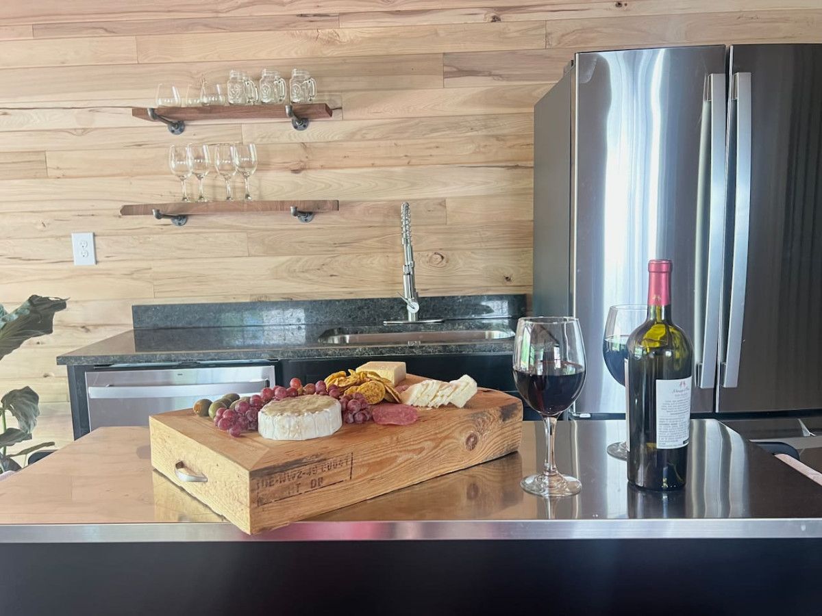 A kitchen with a wooden countertop, a stainless steel refrigerator, and a wine bottle.