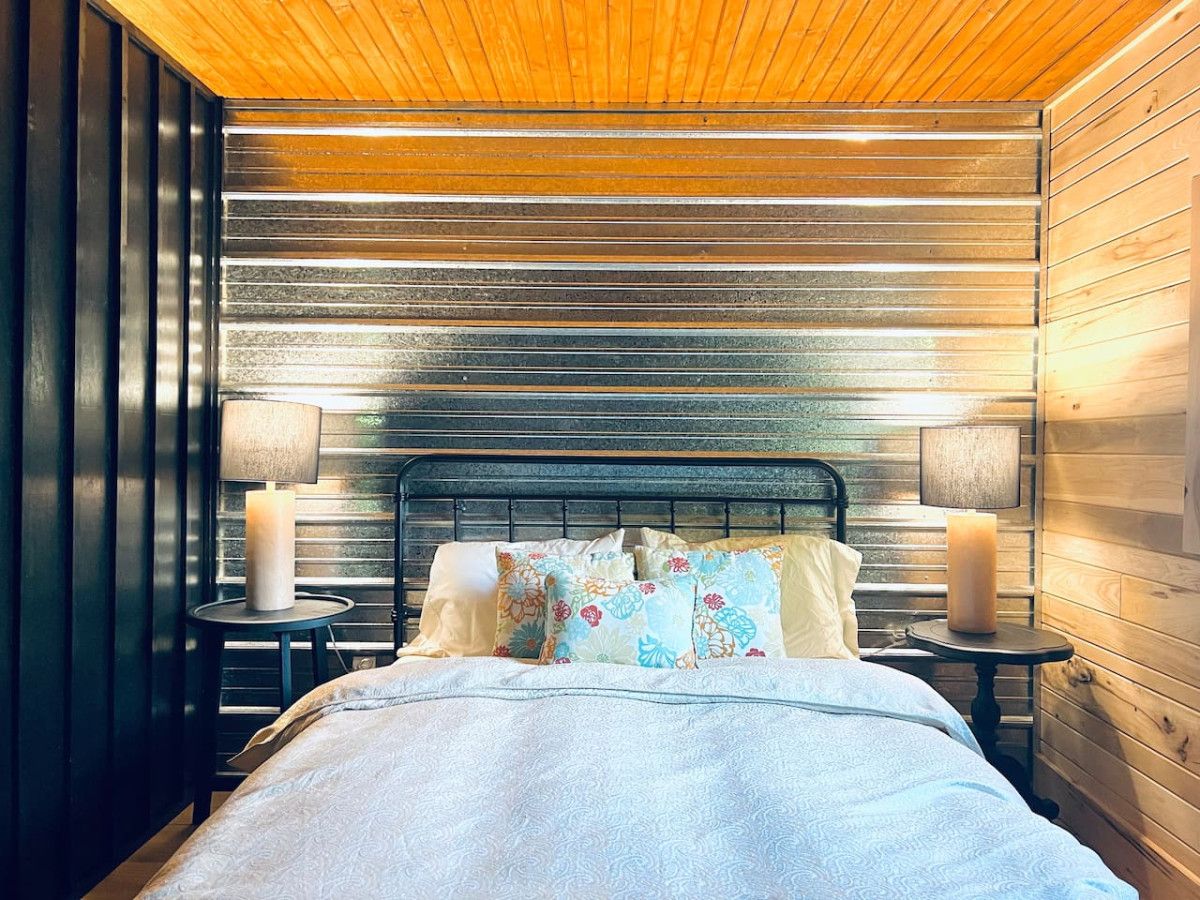 A bedroom with a bed, two bedside tables, and a wooden ceiling.