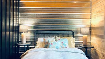A bedroom with a bed, two bedside tables, and a wooden ceiling.