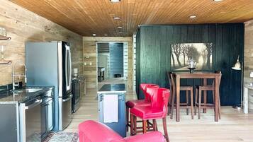 A modern kitchen with stainless steel appliances, a dining area with wooden furniture, and a red sofa.