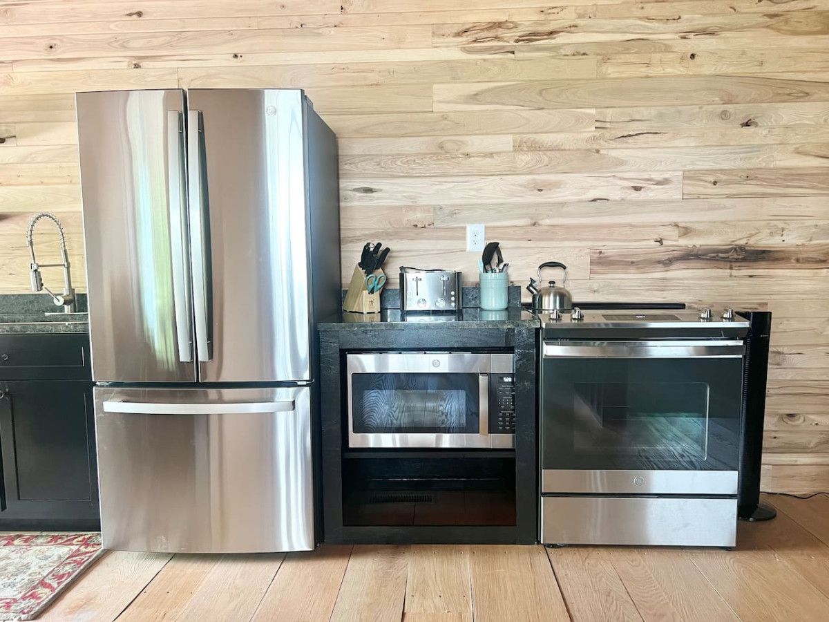 A kitchen with a stainless steel refrigerator, a built-in oven, and a microwave.