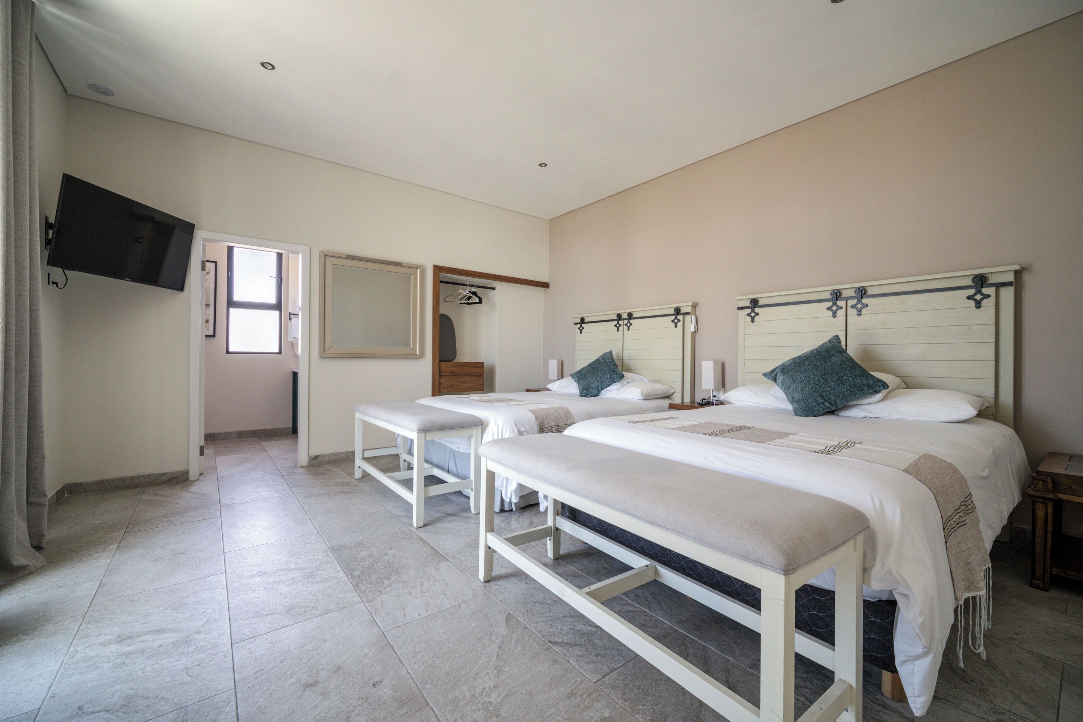Een hotelkamer met twee bedden, een televisie en een badkamer met douche.