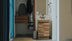A modern bathroom with a wooden vanity, a mirror, and a hairdryer. - Suites Lassa (Ensenada)
