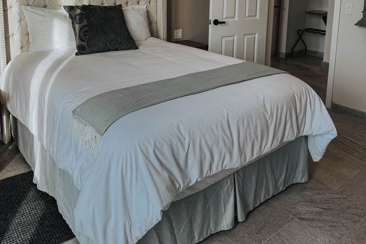 A bedroom with a large bed, a door leading to a closet, and a framed picture on the wall.