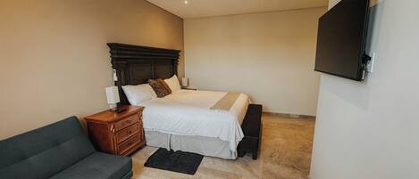 A bedroom with a bed, bedside table, lamp, and a flat-screen TV mounted on the wall.