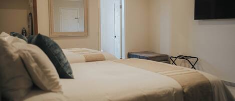 A bedroom with a bed, a bedside table, a mirror, and a TV mounted on the wall.