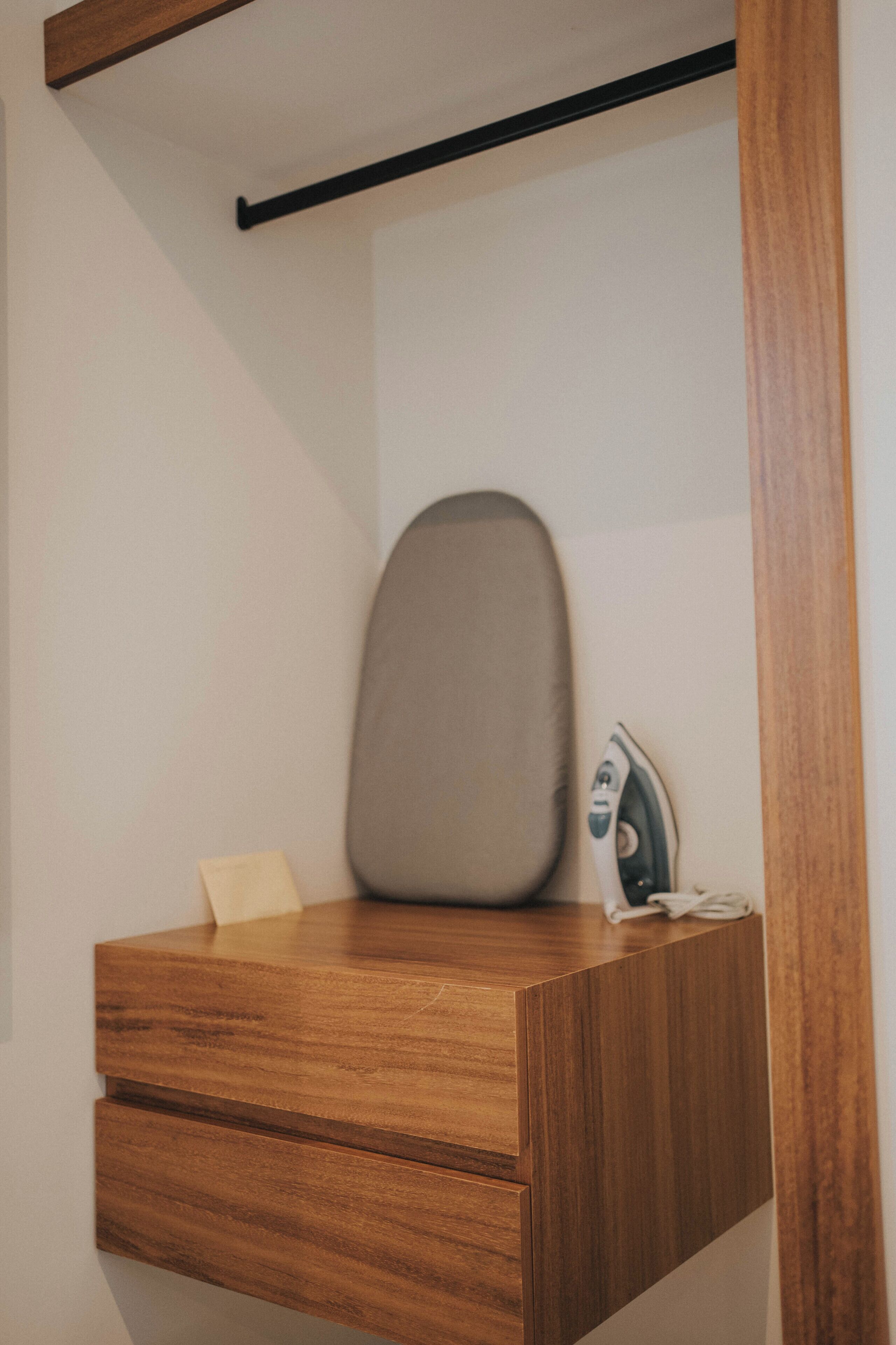 A wooden desk with a grey ironing board and an iron.