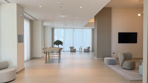 A spacious living area with a foosball table, comfortable seating, and a large window providing natural light. - HomesGetaway-Luxury 1BRApartment in Forte Downtown (Dubai)