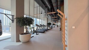 A gym with treadmills, potted plants, and large windows.