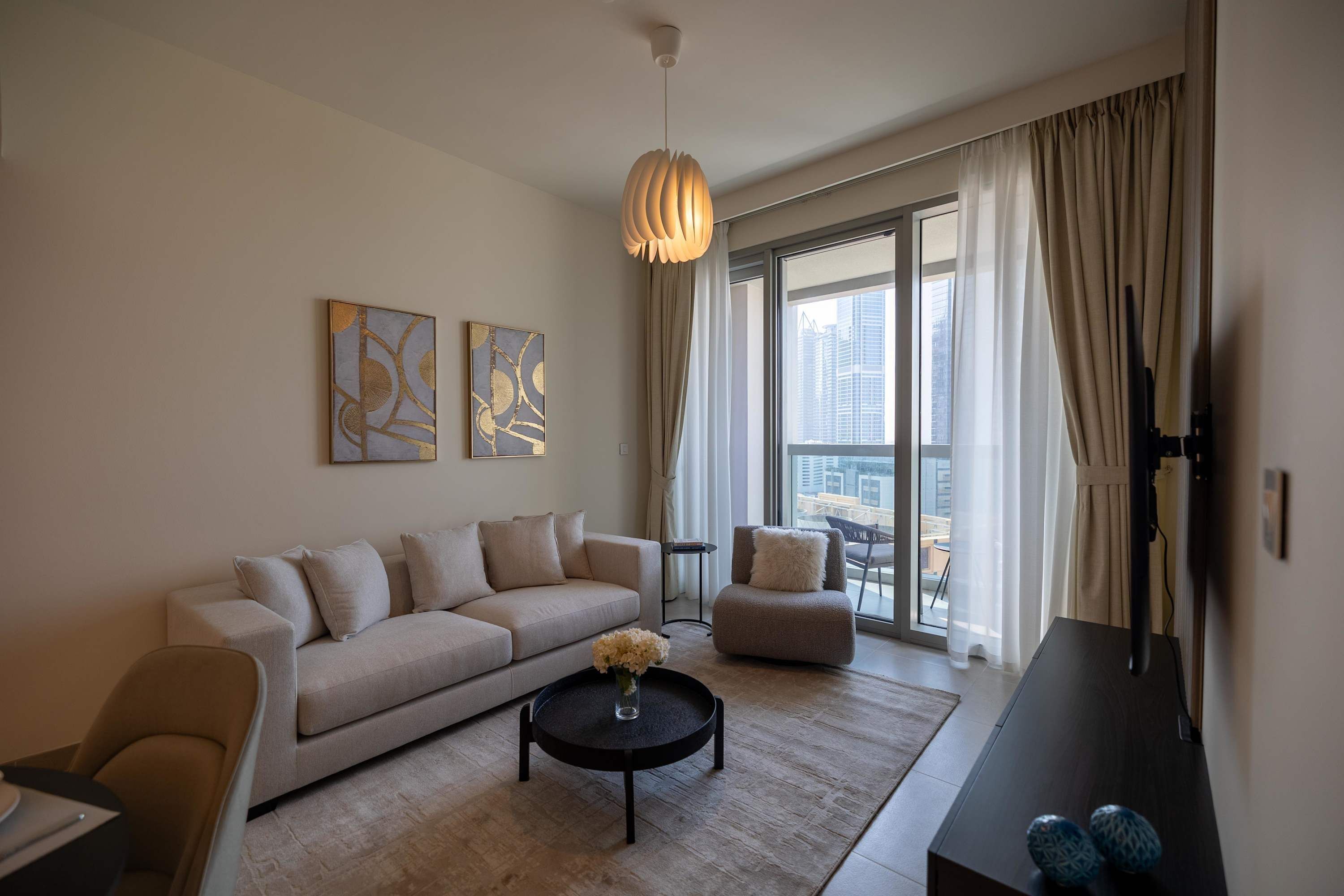 Een moderne woonkamer met een bank, fauteuil, salontafel en kunst aan de muur.