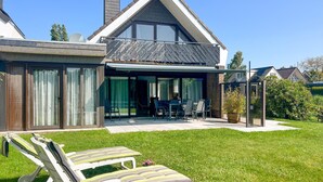 Een modern huis met een grote glazen deur die uitkomt op een overdekt terras.