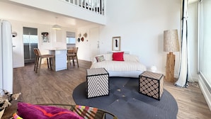 Spazioso loft con soffitto alto, zona pranzo, cucina, soggiorno con un ampio letto e un balcone.