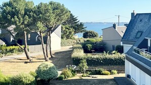 Quartiere residenziale con case, un albero grande e vista sul mare.