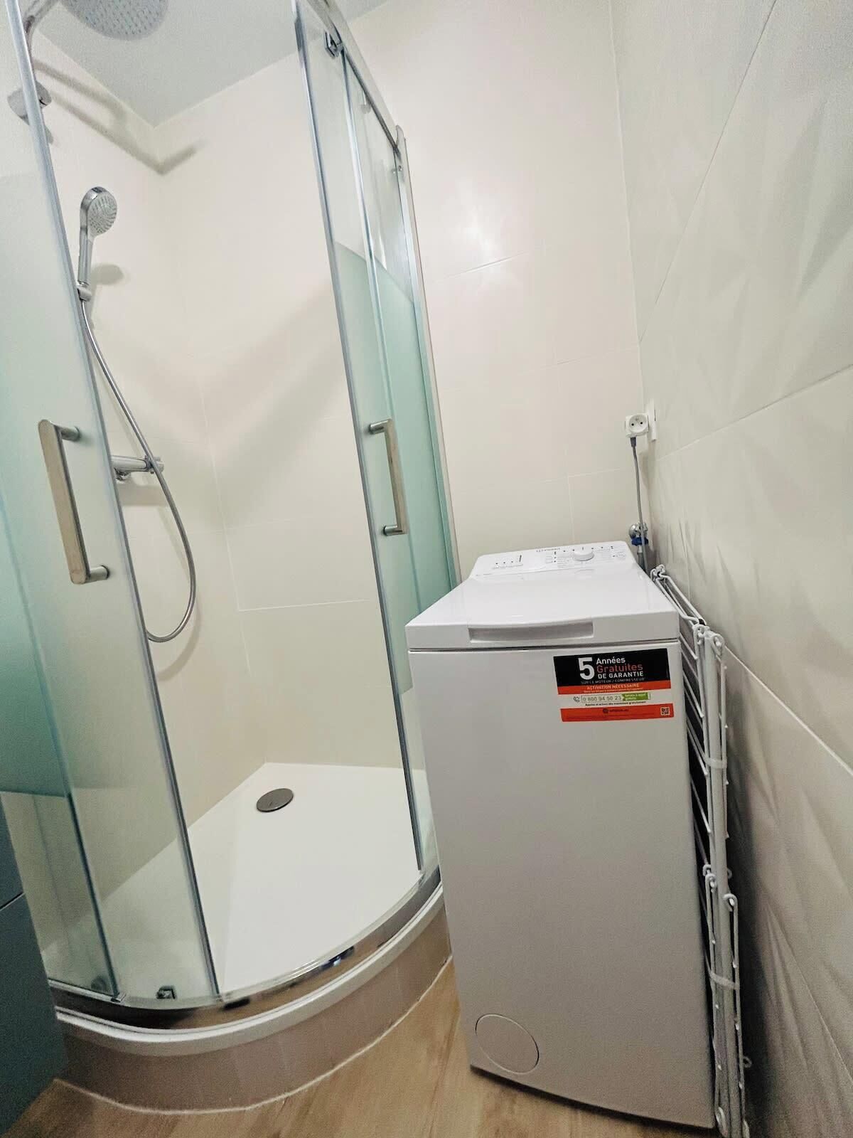 A shower area with a glass door and a white heater unit beside it.