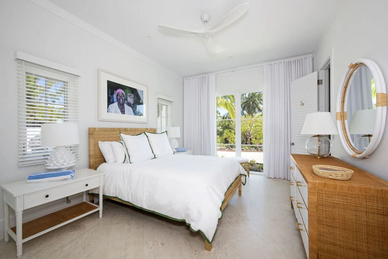 A bedroom with a bed, bedside tables, a dresser, a mirror, and a window with curtains.