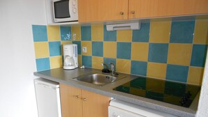 Cocina compacta con microondas, cafetera, lavabo y lavavajillas.