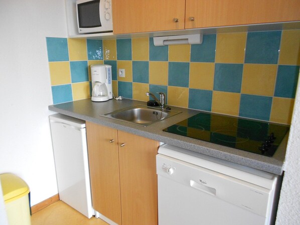 Cocina compacta con microondas, cafetera, lavabo y lavavajillas.